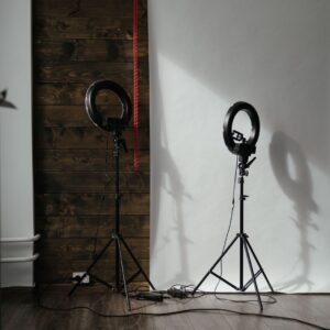 A modern photo studio setup with ring lights and wooden backdrop, ready for a photoshoot.