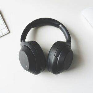 black wireless headphones between Apple Keyboard and Apple Magic Mouse on white surface